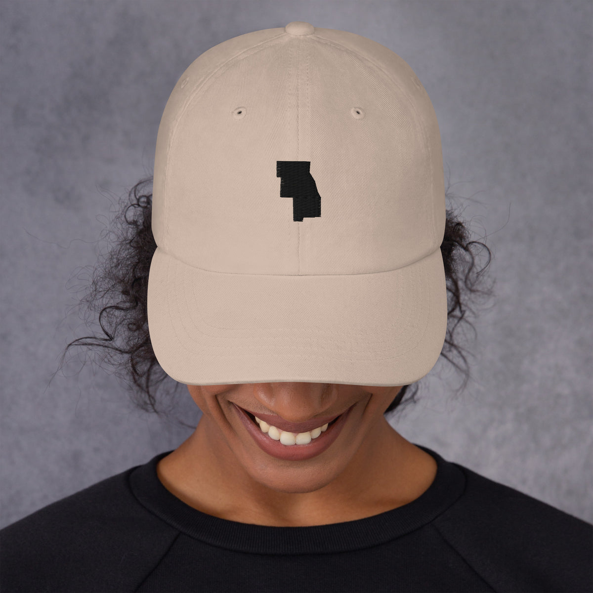 Six County Dad Hat, front on a model, Stone: the six counties stitched in black as one shape.