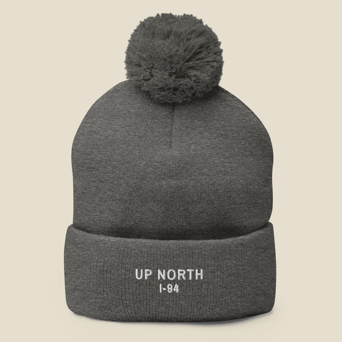Up North Pom Beanie, front, Heather Grey: UP NORTH over I-94 stitched in white on the cuff, pom on top.