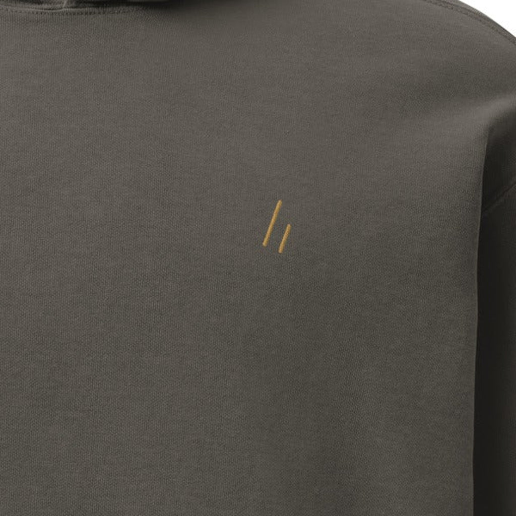 Hoodie, chest close-up, Pepper: the double slanted line mark stitched small in gold thread.