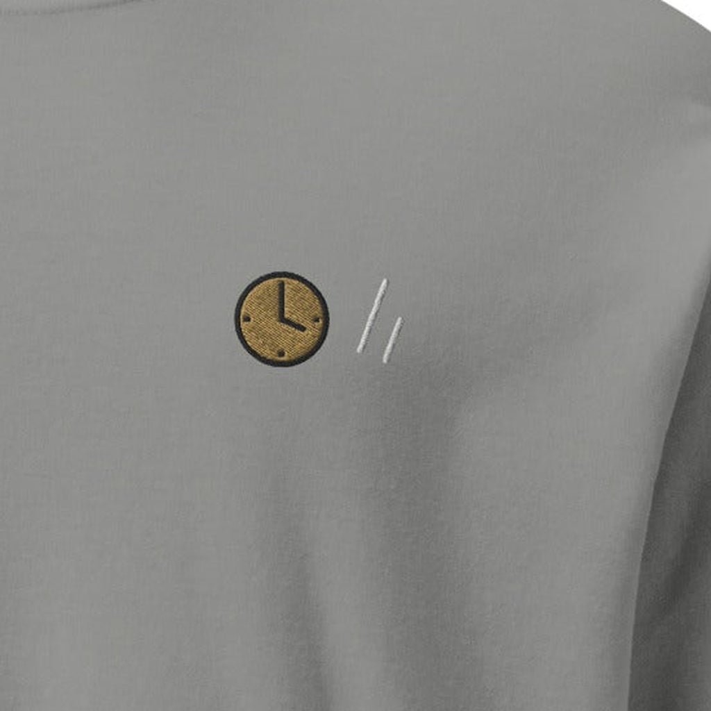 The Square Long Sleeve, chest close-up, Lake Effect (Grey): the clock and the double slanted line mark.