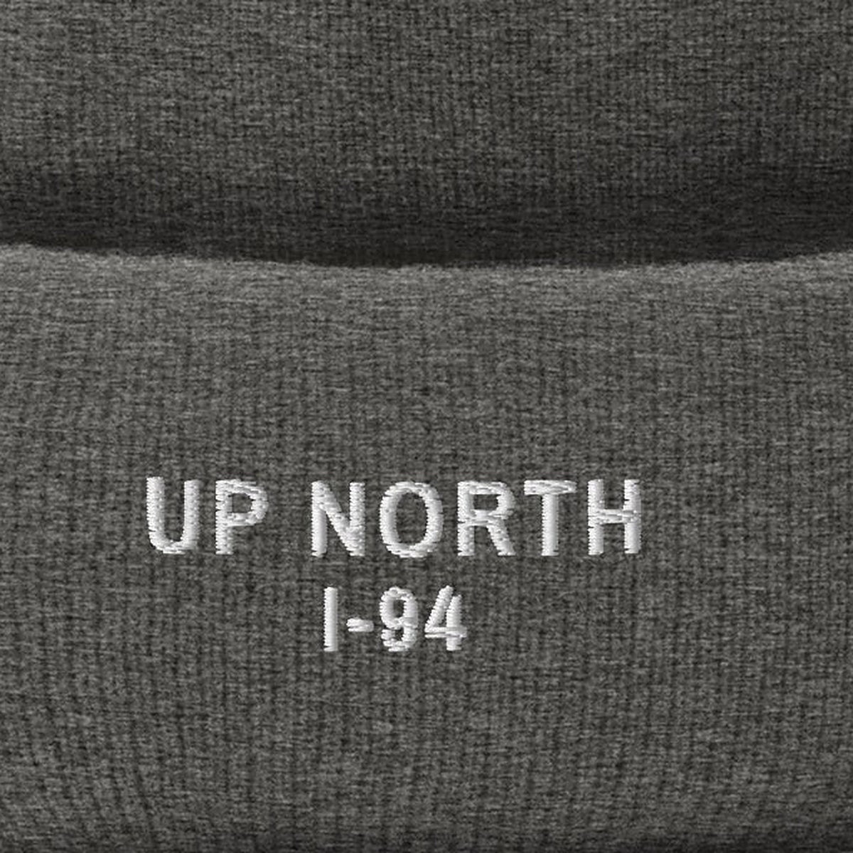 Up North Pom Beanie, cuff close-up, Heather Grey: UP NORTH over I-94 stitched in white.
